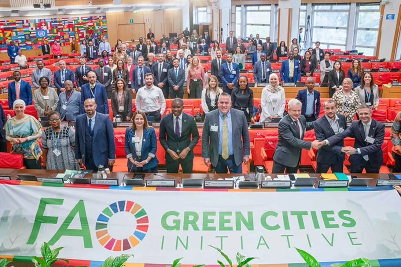 A diverse group of individuals stands in front of a green cities initiative banner, promoting environmental sustainability.
