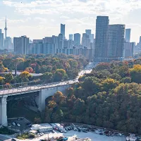 A scenic view of a bridge spanning a river, surrounded by lush greenery and a clear blue sky.