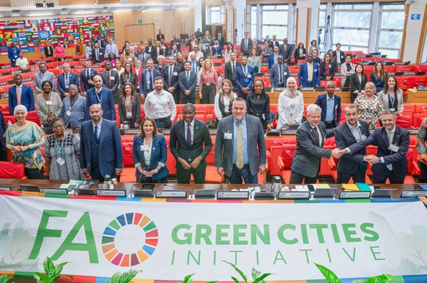 A diverse group of individuals stands in front of a green cities initiative banner, promoting environmental sustainability.